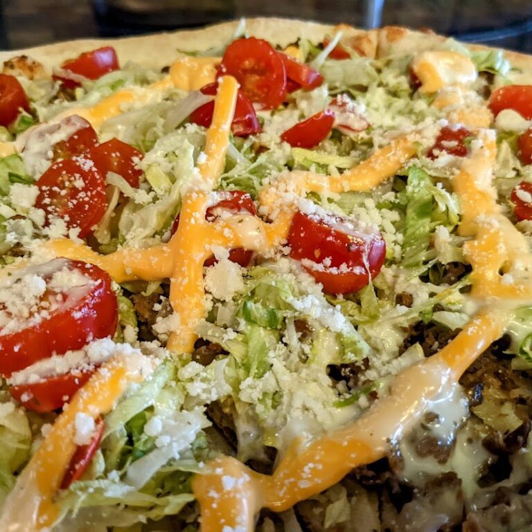 A pizza with tomatoes, lettuce, and cheese.